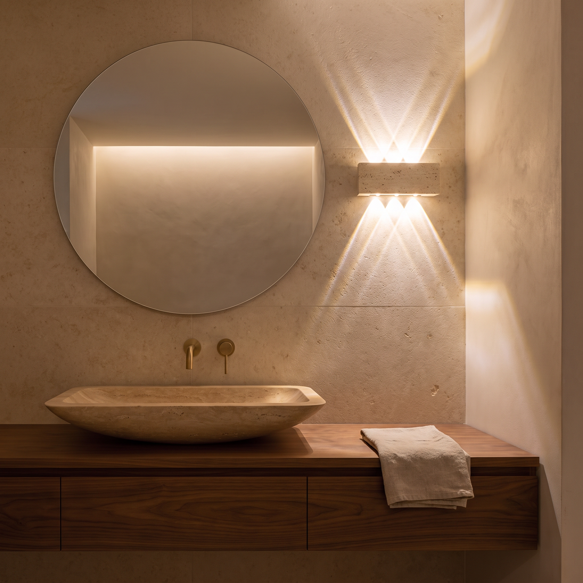 Purbeck travertine wall light beside a round mirror in a limestone bathroom