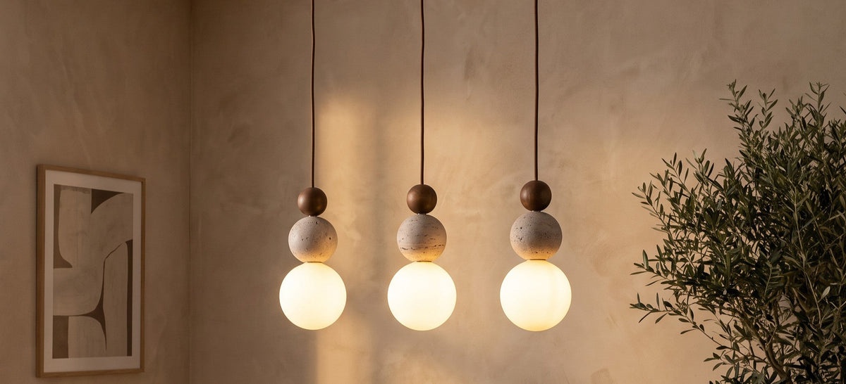 Three Bexley travertine and opal glass pendants above a dining table