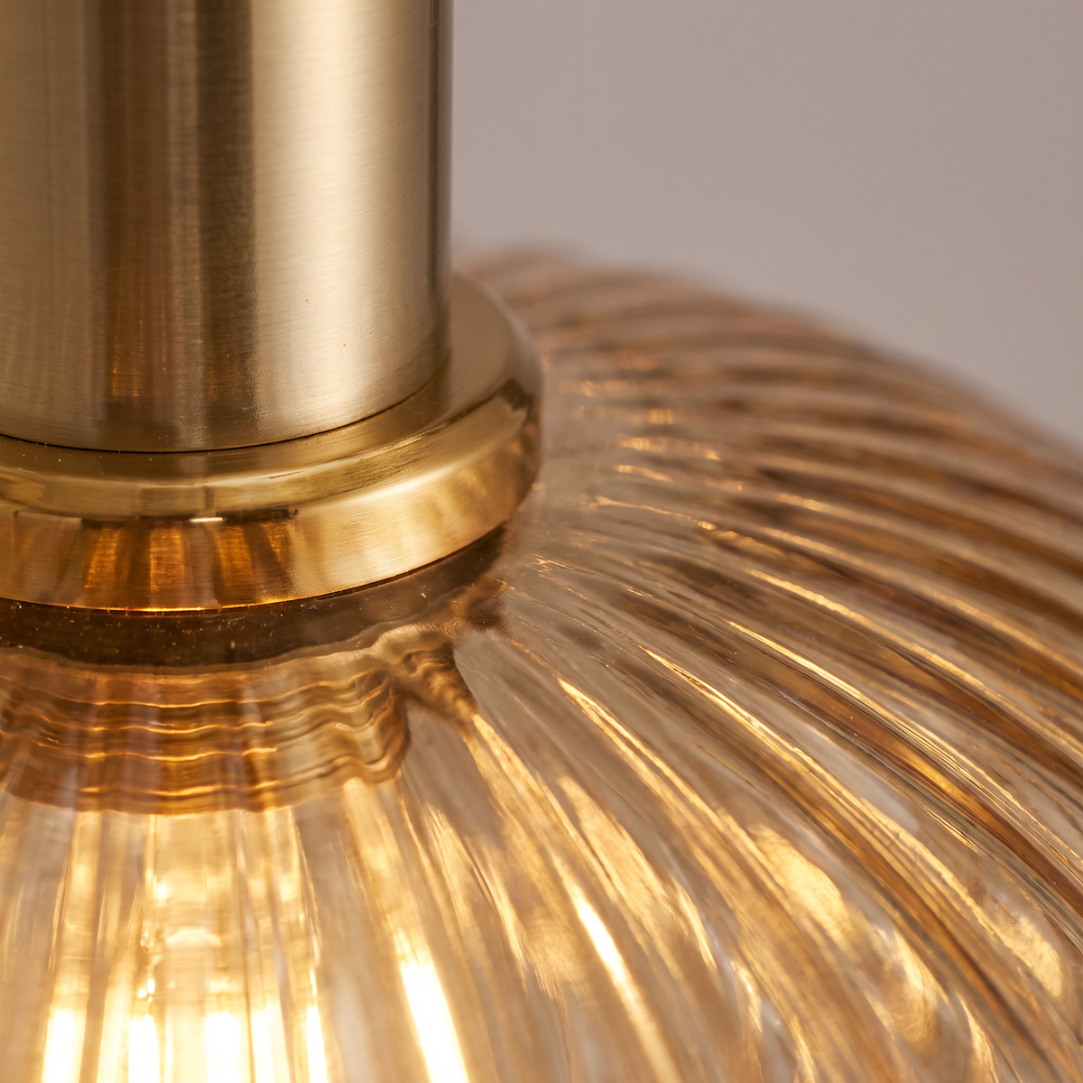 Close up of ribbed amber glass and a polished brass cap