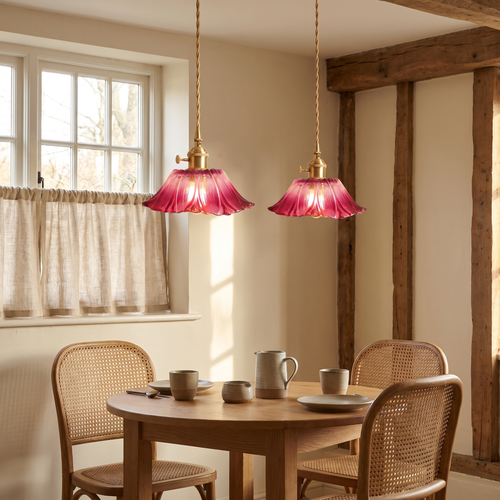 A pair of raspberry Benhall pendants lit over a small breakfast table in a cottage kitchen