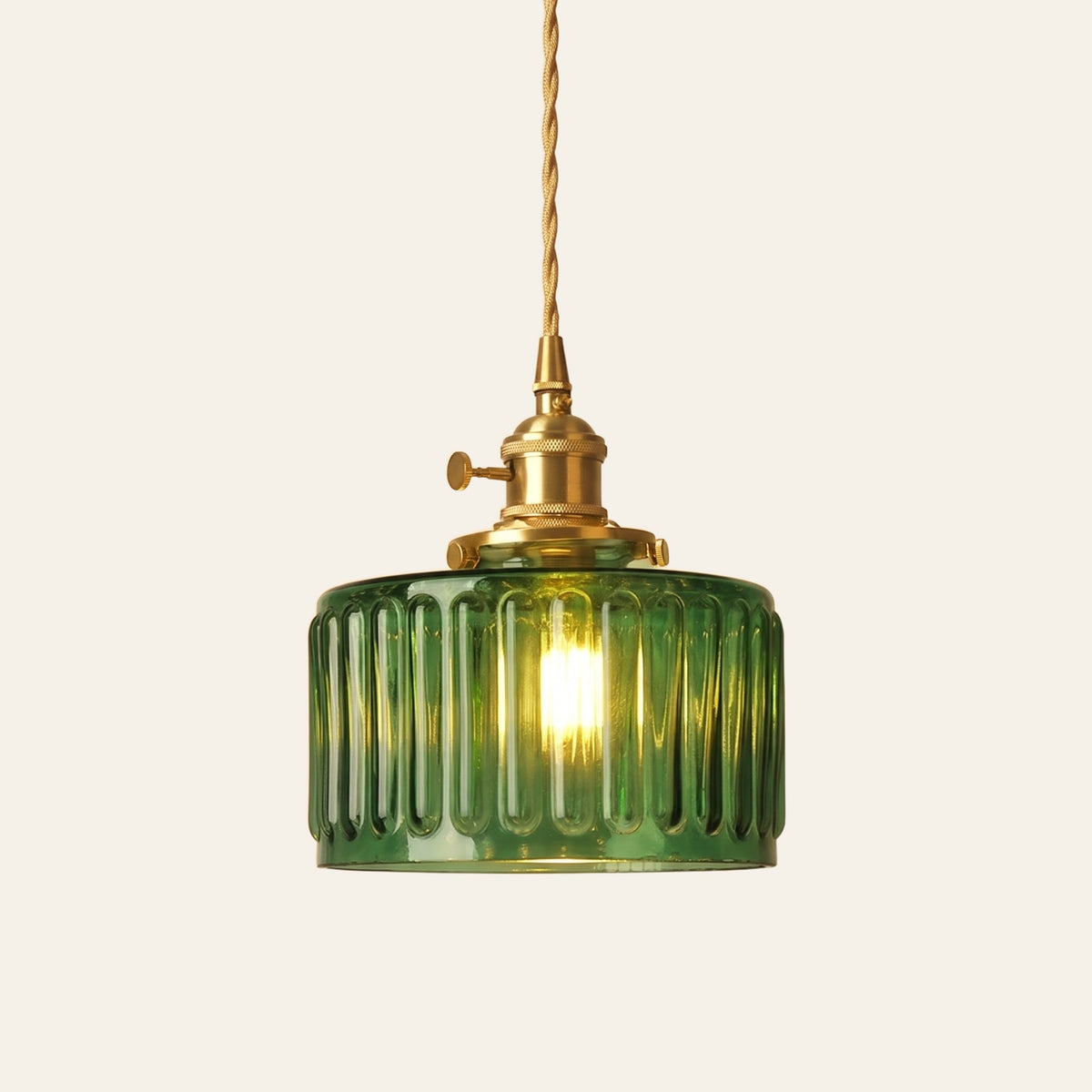 Bildeston ribbed glass drum pendant light in green glass on a brass holder with a twisted cord, cream background