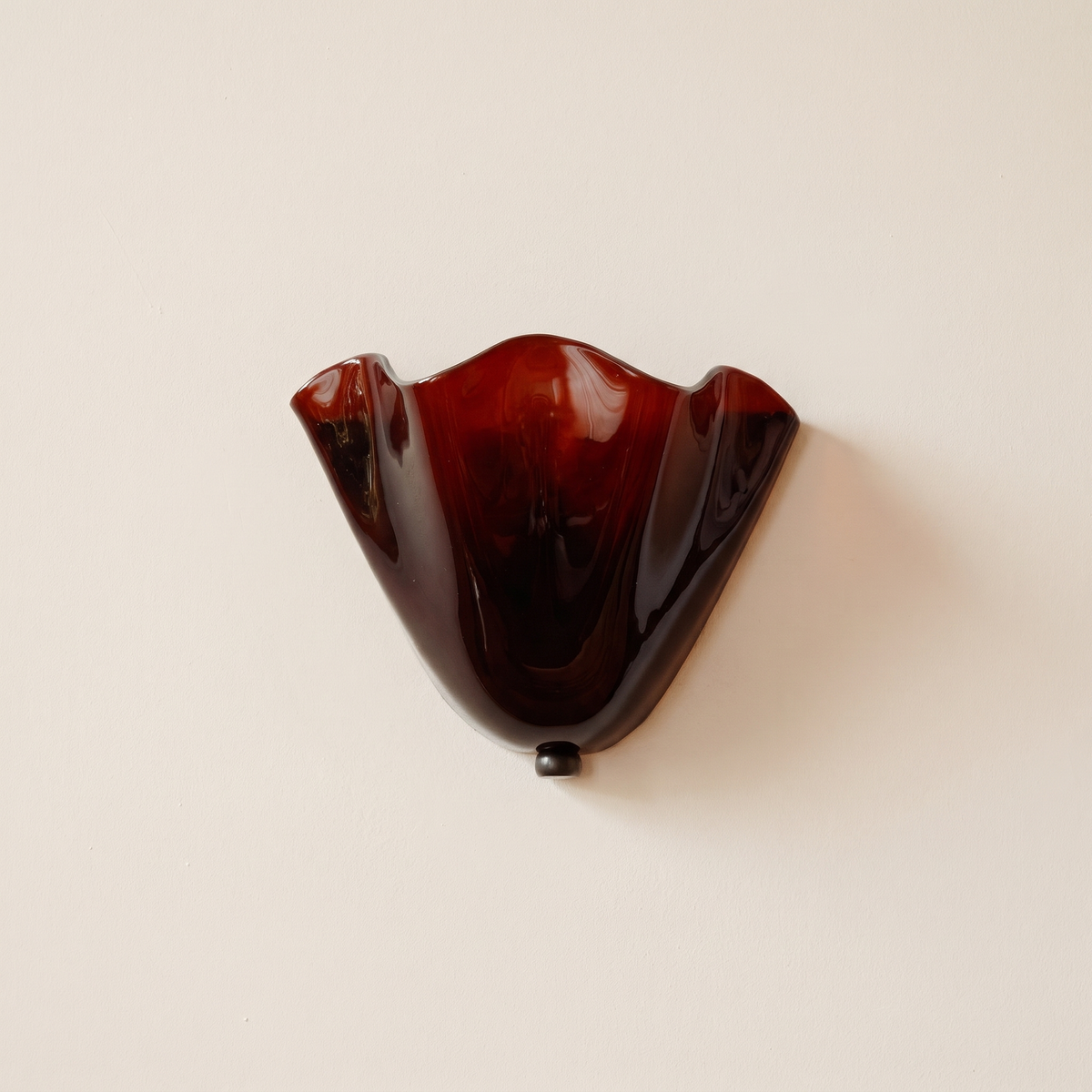 Blythburgh wall light, a folded handkerchief shade of deep garnet glass with a waved rim, on a cream wall