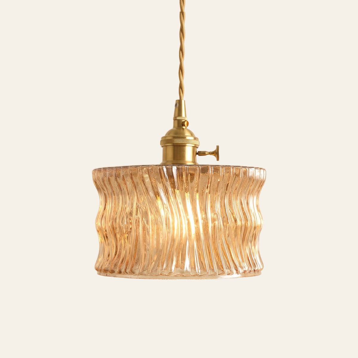 Boxford wavy ribbed glass cylinder pendant light in champagne amber glass on a brass holder with a twisted cord, cream background