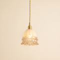 Bramfield pendant light with a milky fluted glass bell, beaded band and clear ruffled rim on a brass holder, cream background