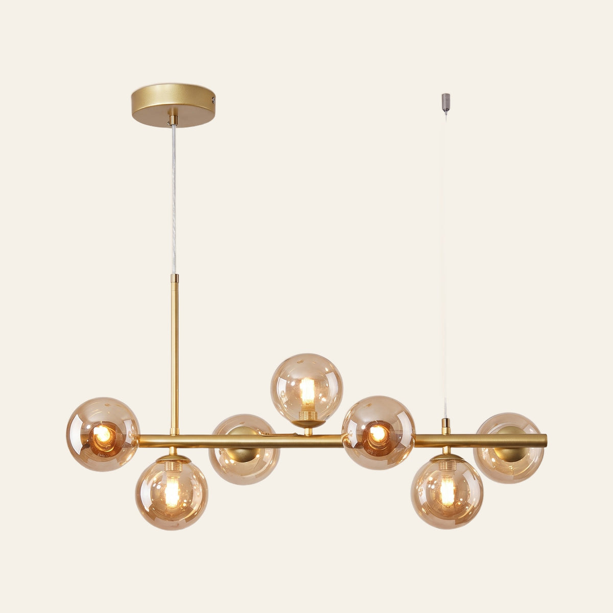 Brandeston linear chandelier with seven amber glass globes on a 65 cm gold bar, cream background