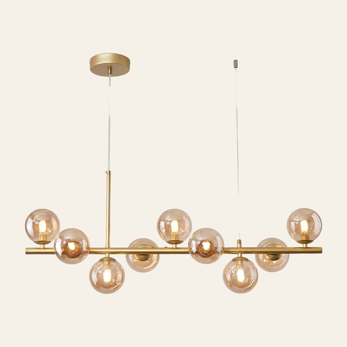 Brandeston linear chandelier with nine amber glass globes on an 83 cm gold bar, cream background