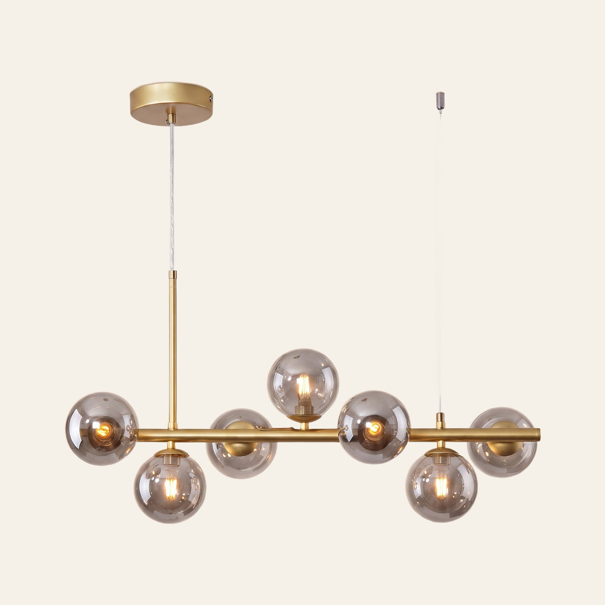 Brandeston linear chandelier with seven smoked glass globes on a 65 cm gold bar, cream background