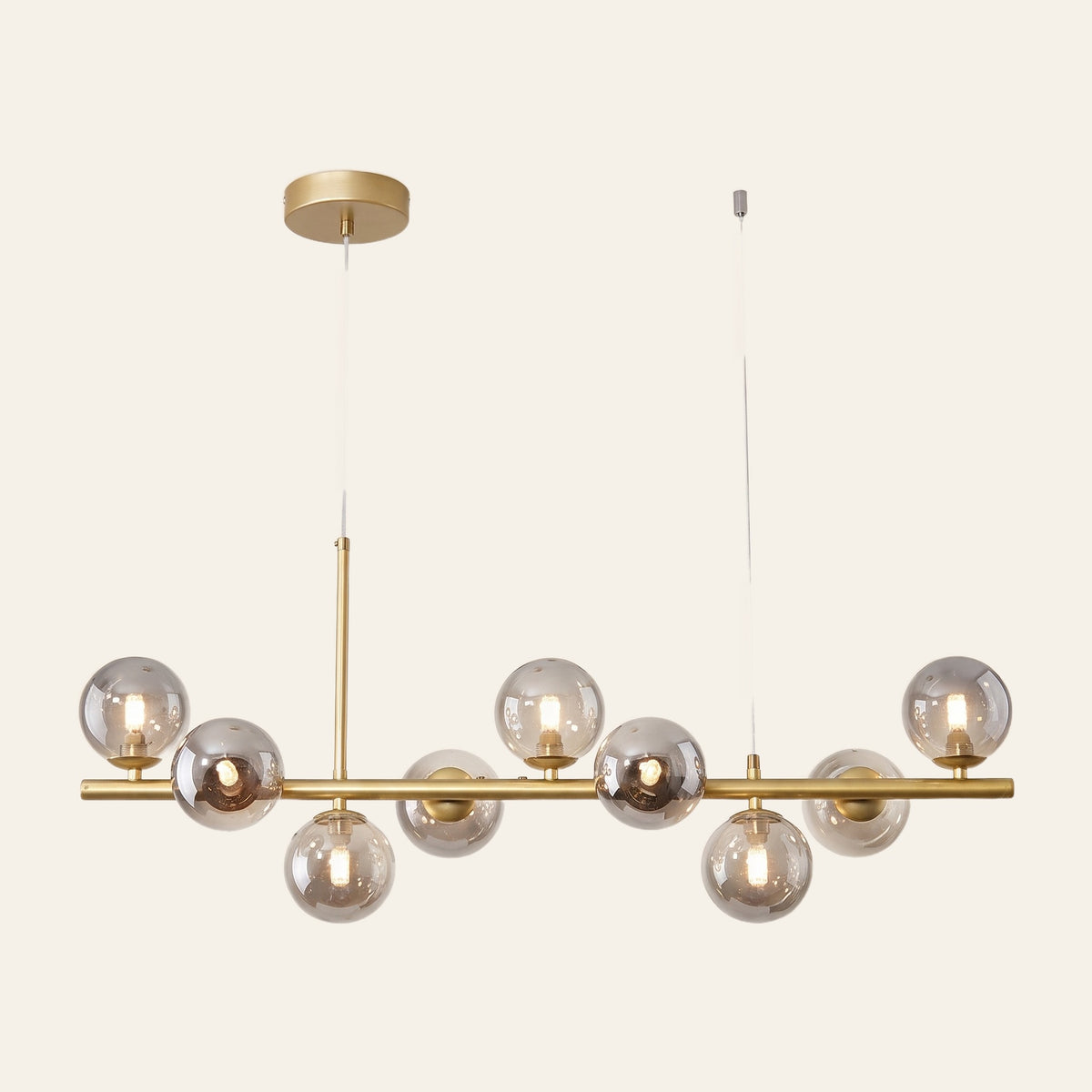 Brandeston linear chandelier with nine smoked glass globes on an 83 cm gold bar, cream background