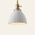 Brantham pendant light, a matte white ribbed ceramic bell shade on a brass finish holder with a turn switch, lit, cream background