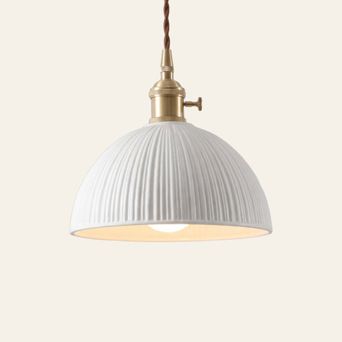 Brantham pendant light, a wide matte white ribbed ceramic half dome on a brass finish holder with a turn switch, lit, cream background