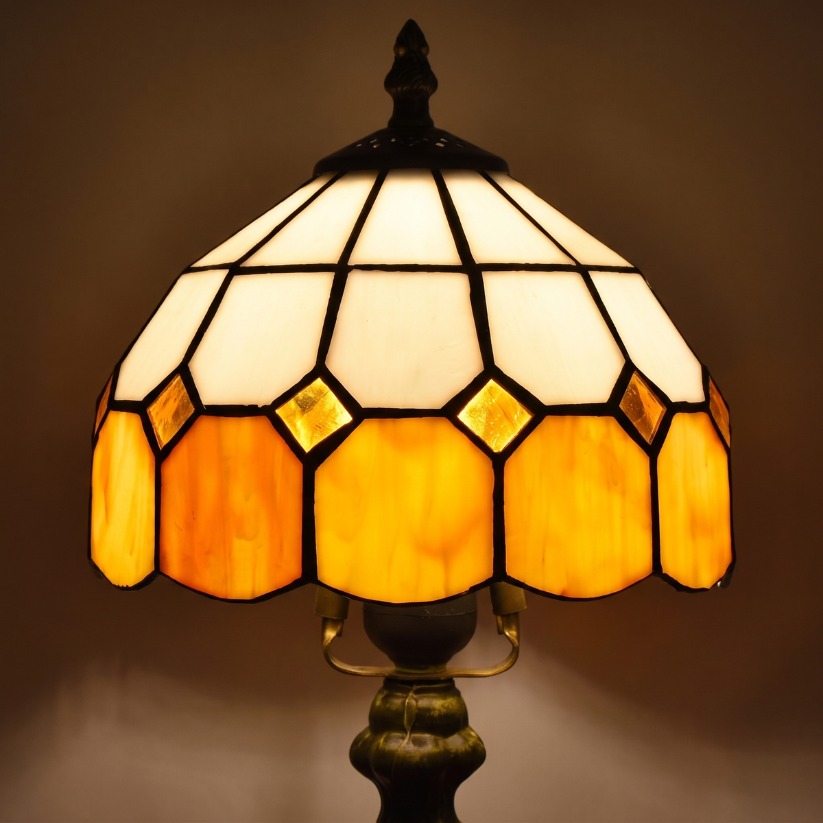 Close up of the lit amber Cavendish shade: ivory panels, amber diamonds and a scalloped amber band in dark leading