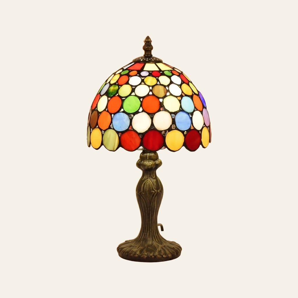 Chelsworth stained glass table lamp, a dome of round glass jewels in red, orange, yellow, blue and green on a dark bronze finish base, lit, cream background