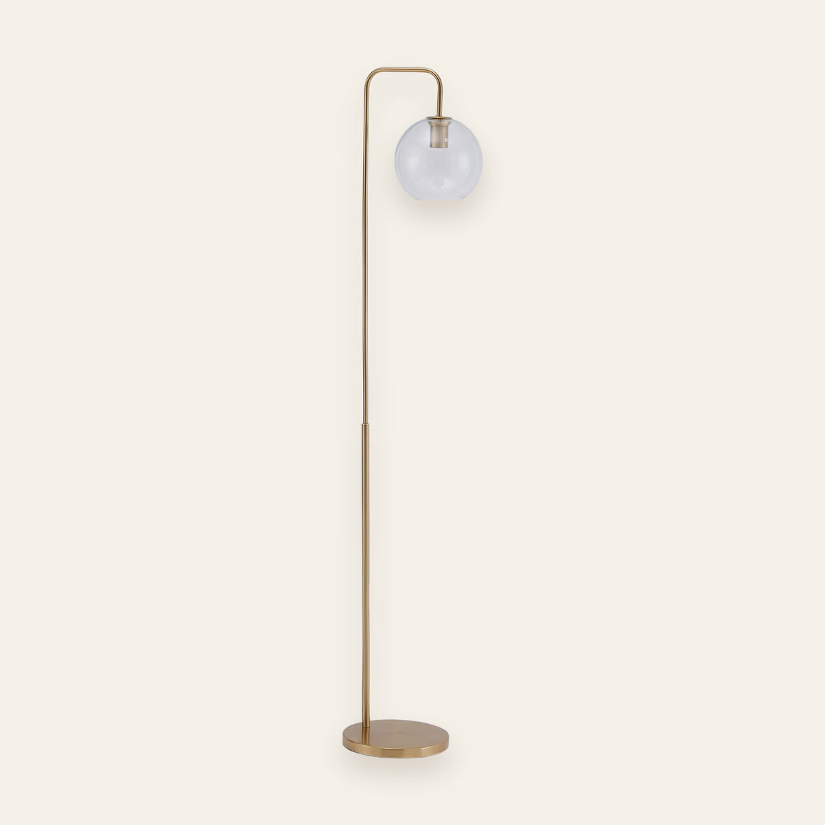 Clifton gold arc floor lamp with a clear glass globe on a cream background