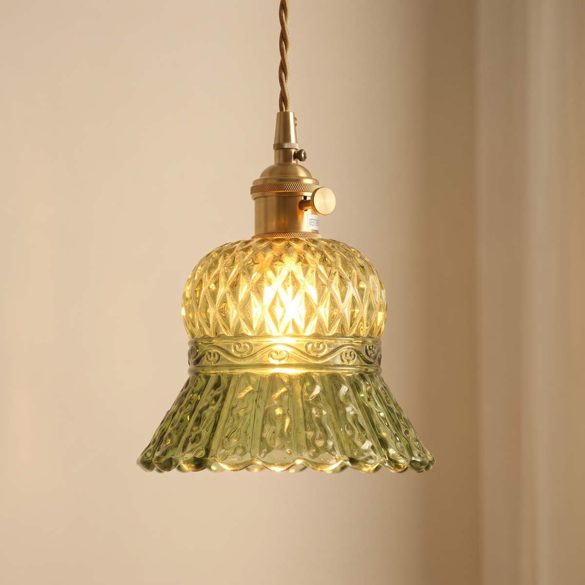 Close up of the green Cratfield diamond pattern glass, moulded band and scalloped hem, lit