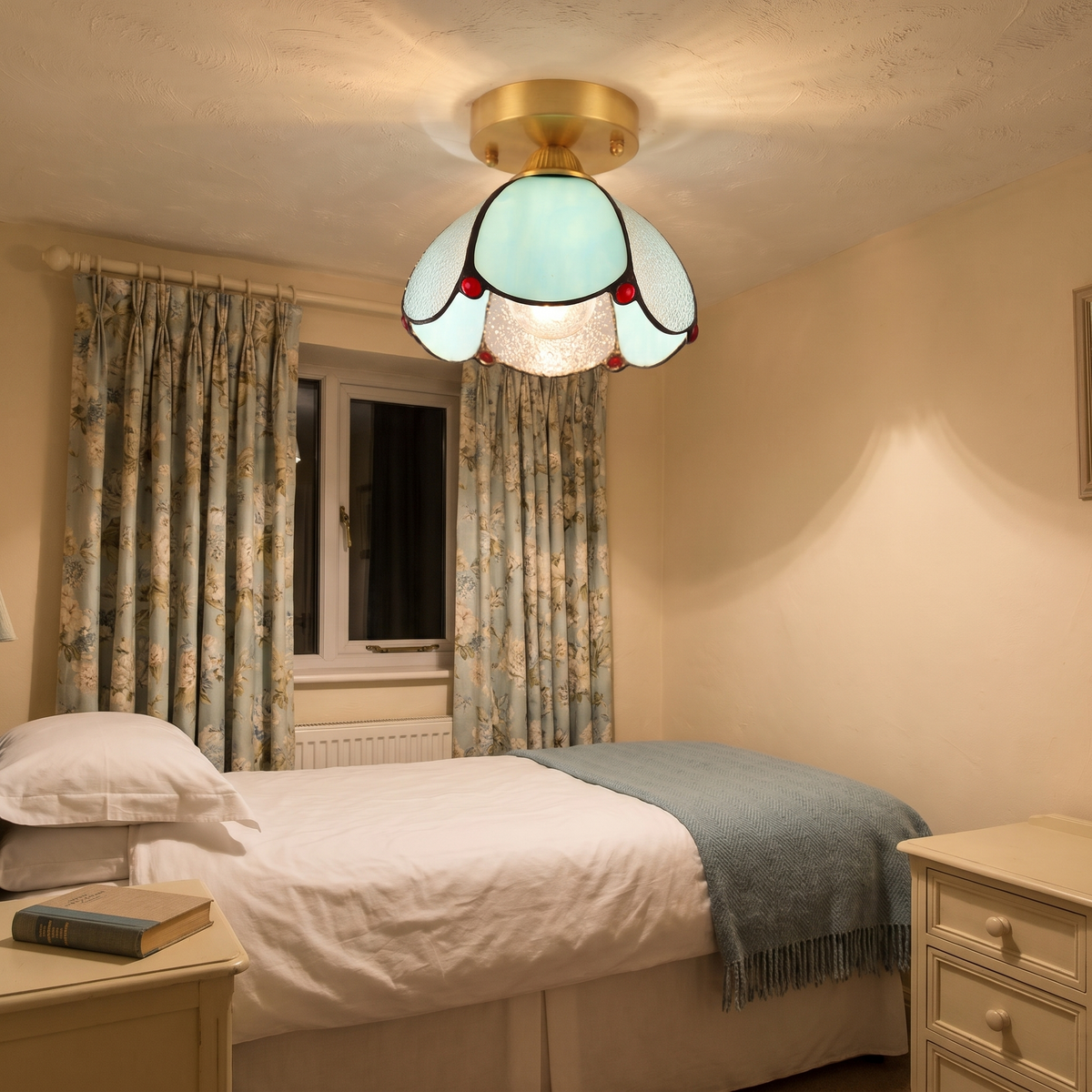 A lit Darsham stained glass tulip ceiling light in a small bedroom