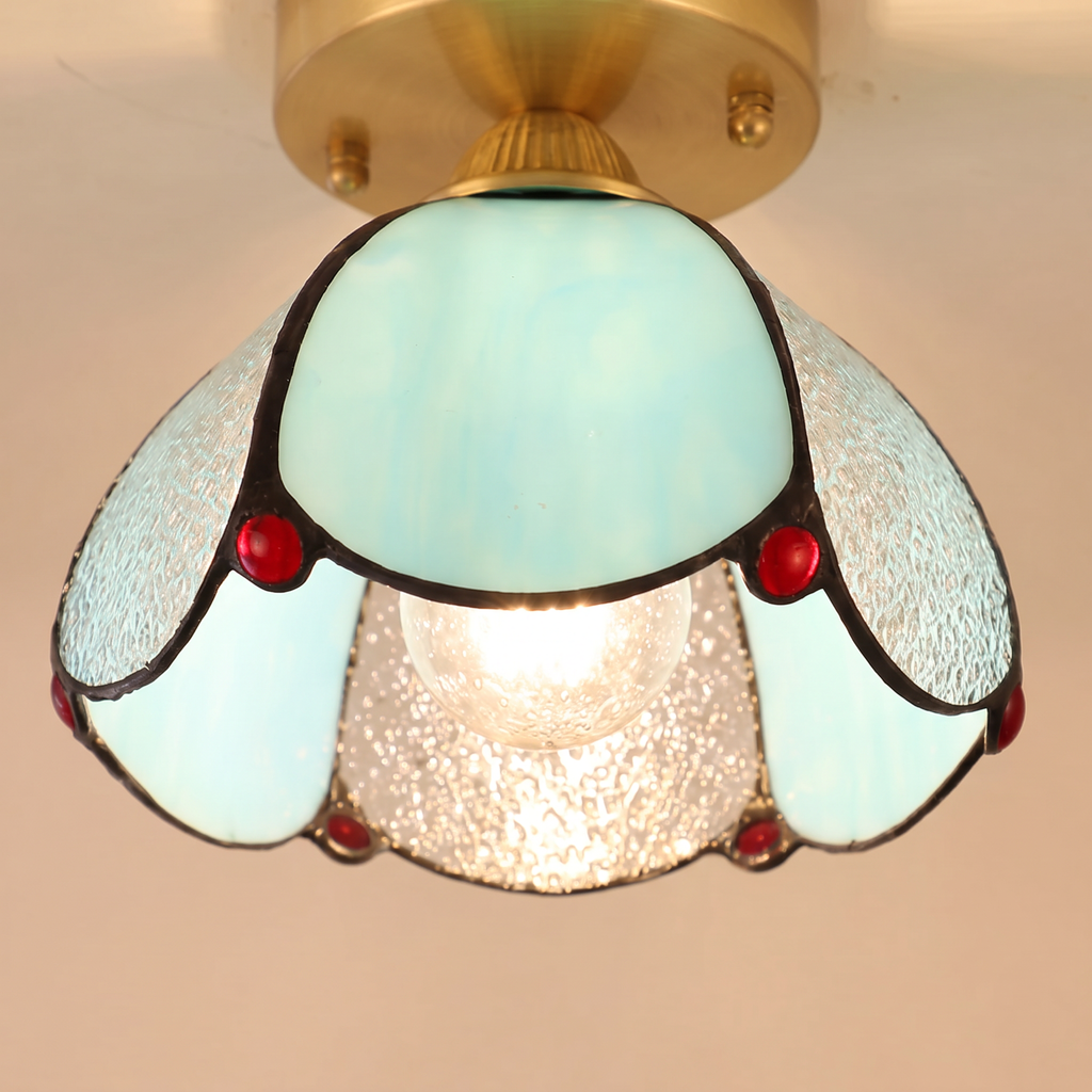 Close up of a lit Darsham shade showing the aqua opal petals, clear seeded glass and red glass jewels
