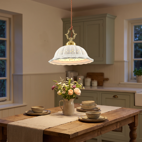 A lit Dennington pierced ceramic pendant over a farmhouse kitchen table