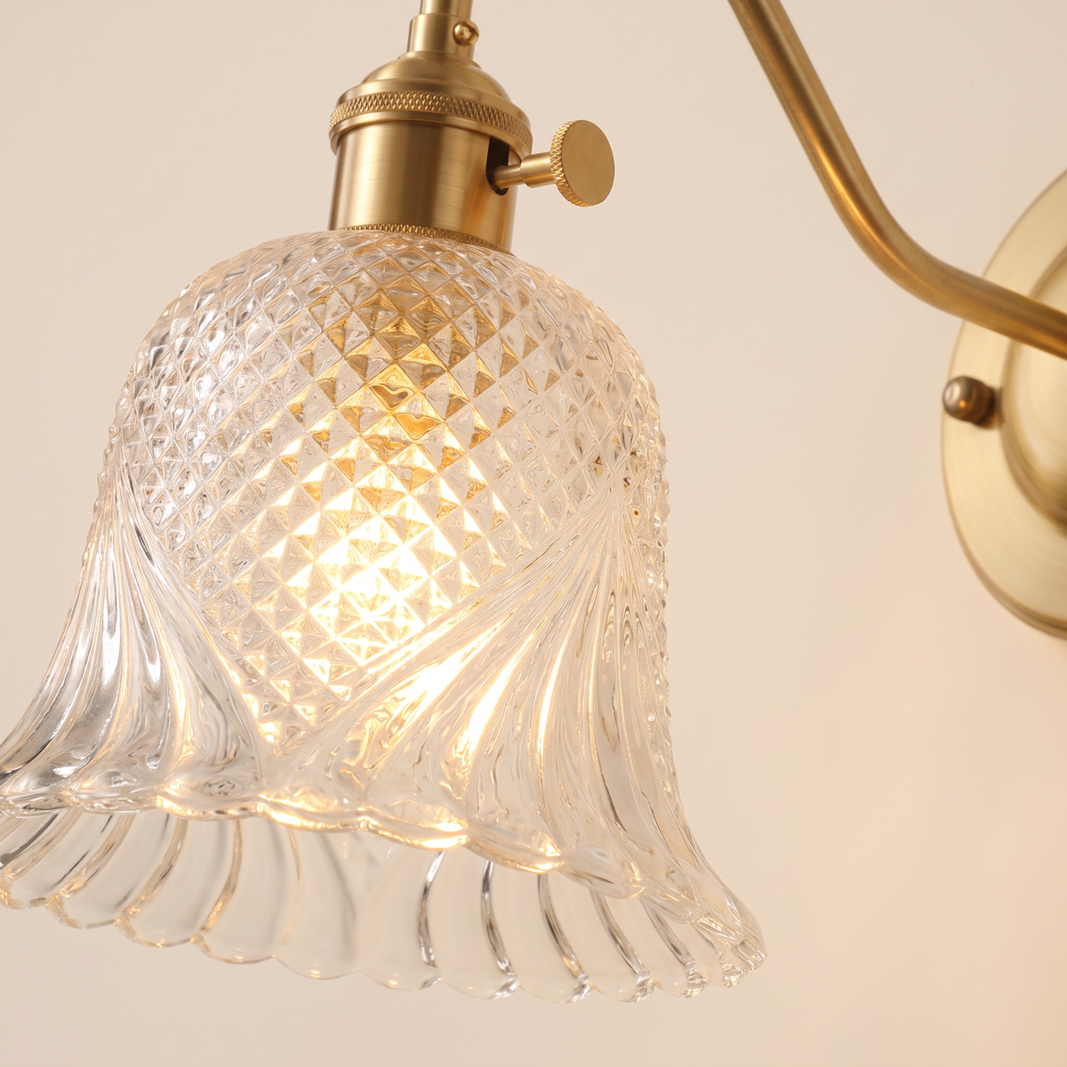 Close up of the Dunwich clear diamond cut glass bell shade, brass holder and turn knob switch