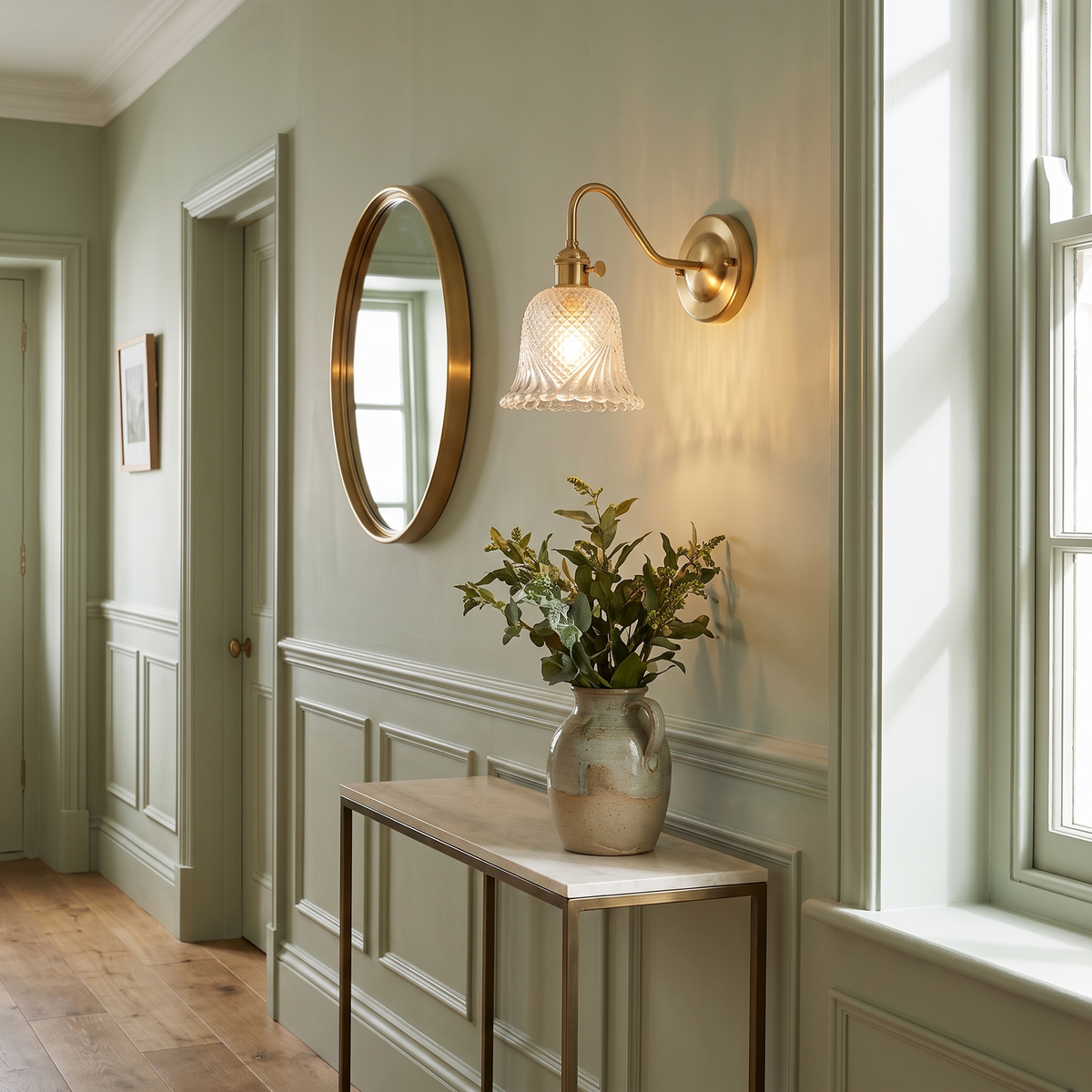 Dunwich diamond cut glass wall light beside a round mirror in a green hallway