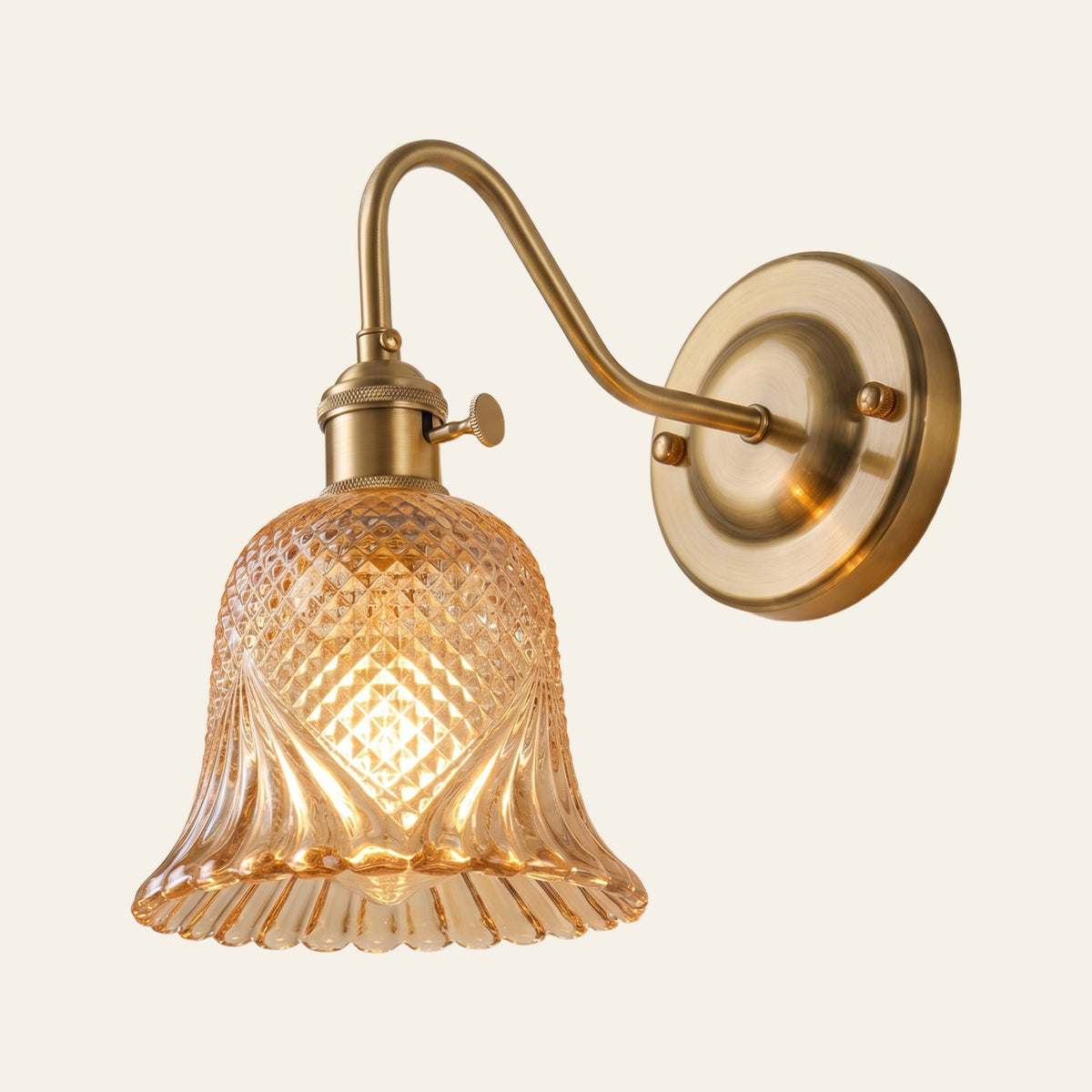 Dunwich wall light with an amber diamond cut glass bell shade on a brass swan neck arm, lit