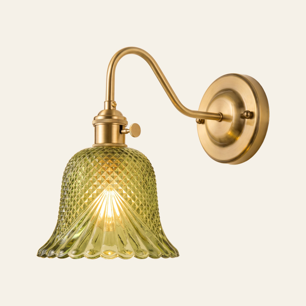 Dunwich wall light with a green diamond cut glass bell shade on a brass swan neck arm, lit