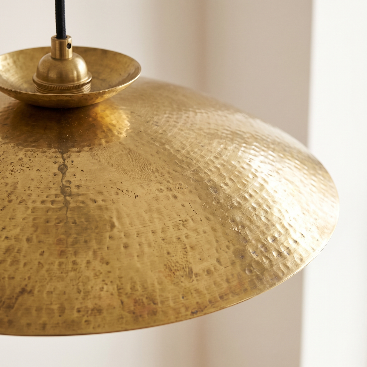 Close detail of the hand hammered brass surface of a pendant light
