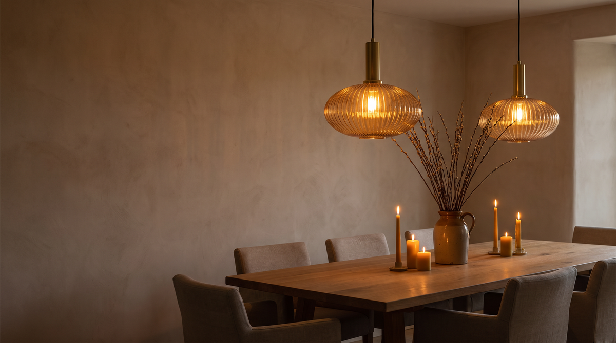 Two amber ribbed glass pendants glowing over an oak dining table at dusk