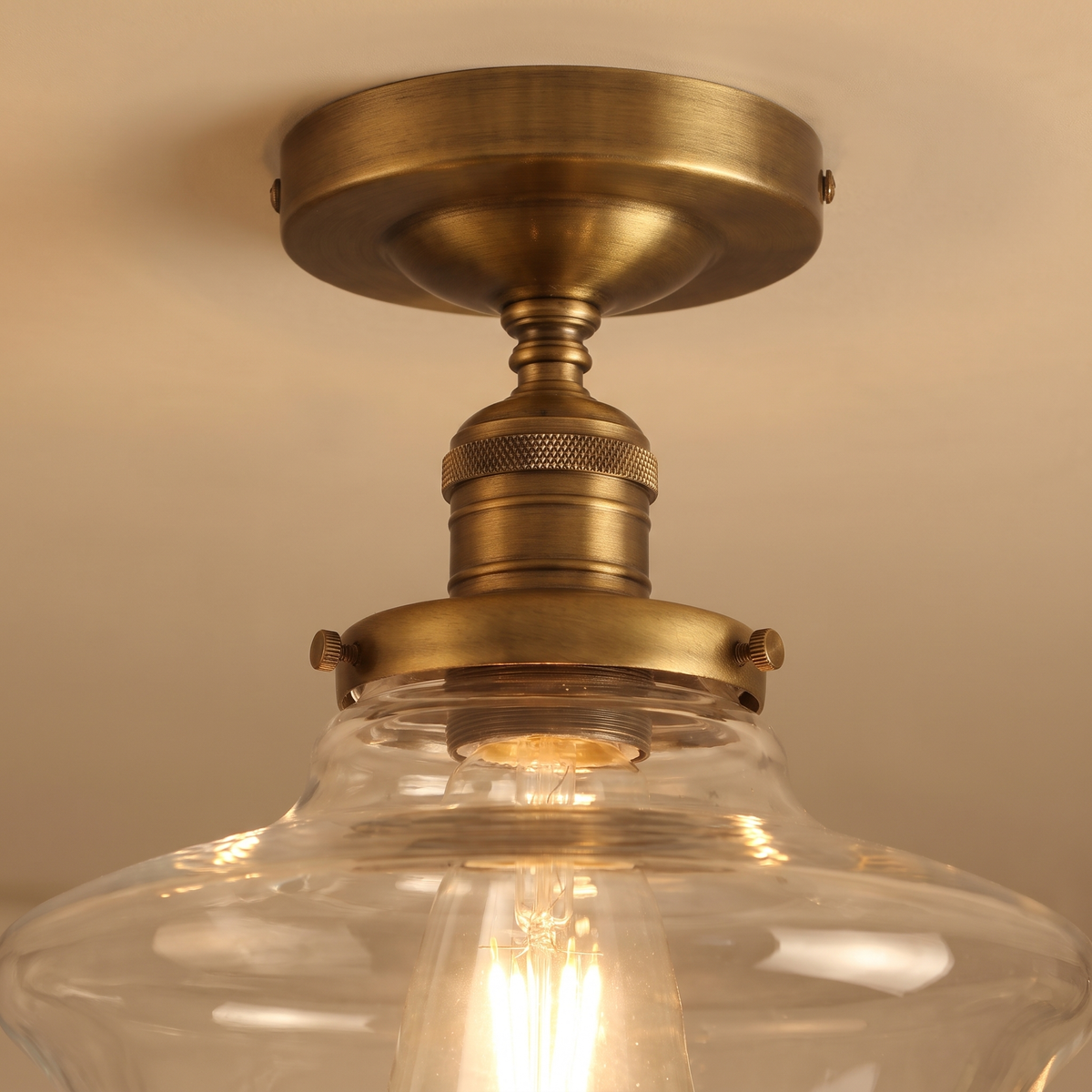 Close up of the Ely clear schoolhouse glass shade, glowing filament bulb and antique brass lamp holder
