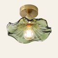 Framlingham ceiling light with a wavy green glass lotus leaf shade on a brass stem, lit