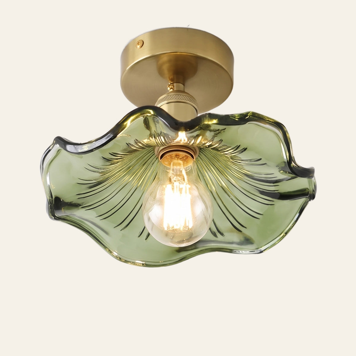 Framlingham ceiling light with a wavy green glass lotus leaf shade on a brass stem, lit