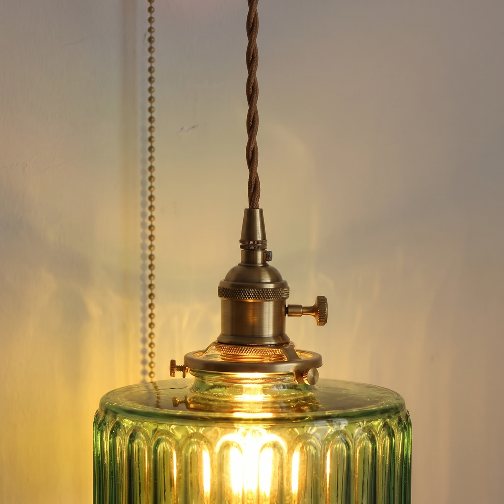 Close up of the Framsden braided cord, knurled lamp holder with its turn knob and the green ribbed glass glowing warm