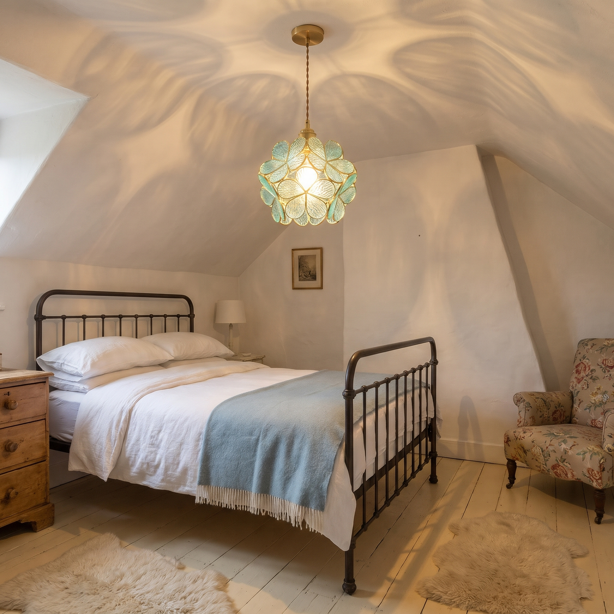 A lit aqua Fressingfield glass flower pendant light casting petal patterns on the ceiling of a cottage bedroom