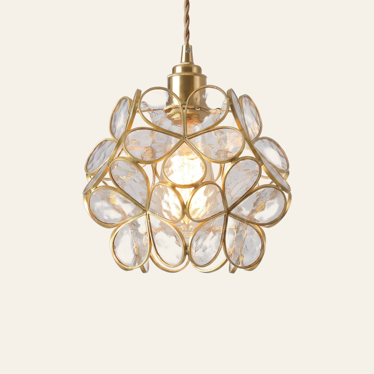 Fressingfield pendant light, a round ball of clear rippled glass flowers in fine gold tone frames, lit, cream background