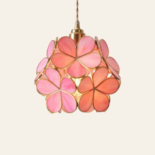 Fressingfield pendant light, a round ball of rose pink rippled glass flowers in fine gold tone frames, lit, cream background