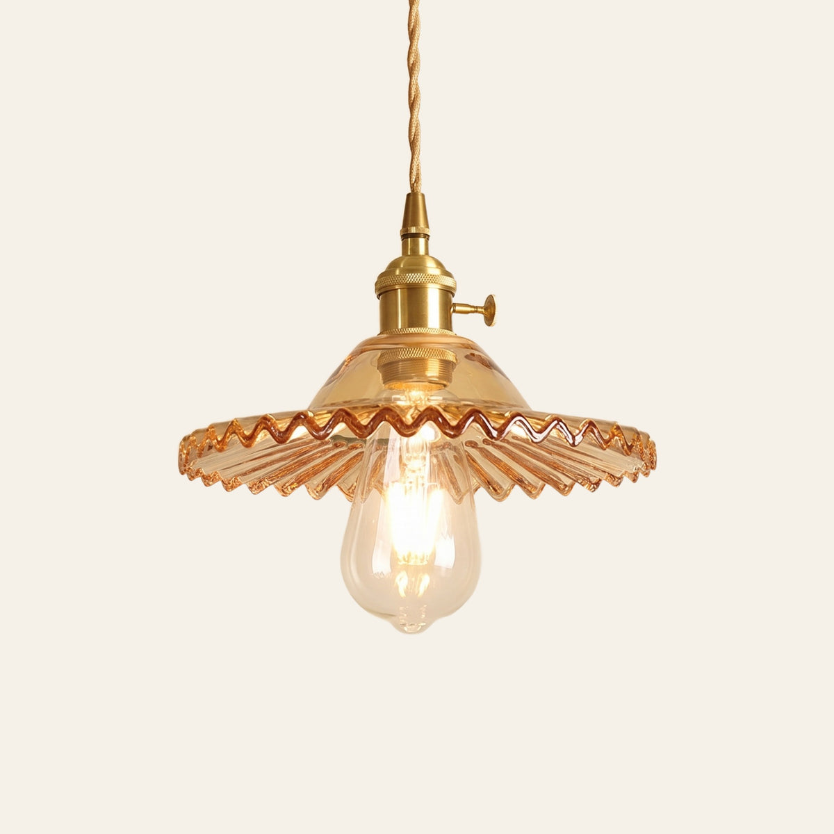 Glemsford fluted glass coolie pendant light in honey amber glass on a brass holder with a twisted cord, cream background