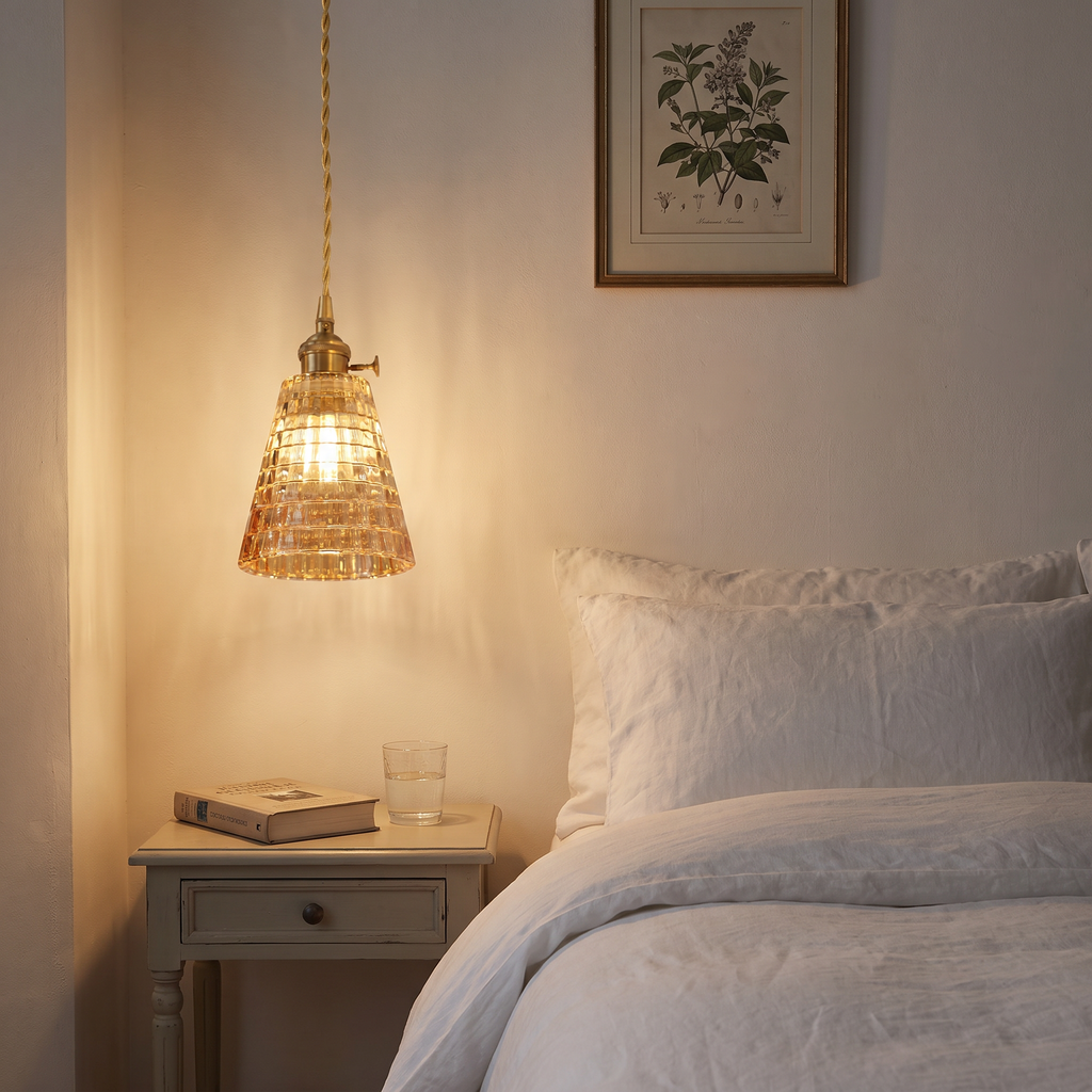 A Hacheston amber cut glass pendant lit low beside a bed