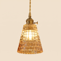Hacheston pendant light with a tall amber cut glass cone shade on a brass holder with a turn switch, cream background
