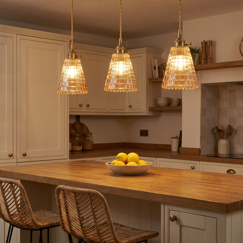 Three lit Hacheston amber cut glass pendants in a row in a kitchen