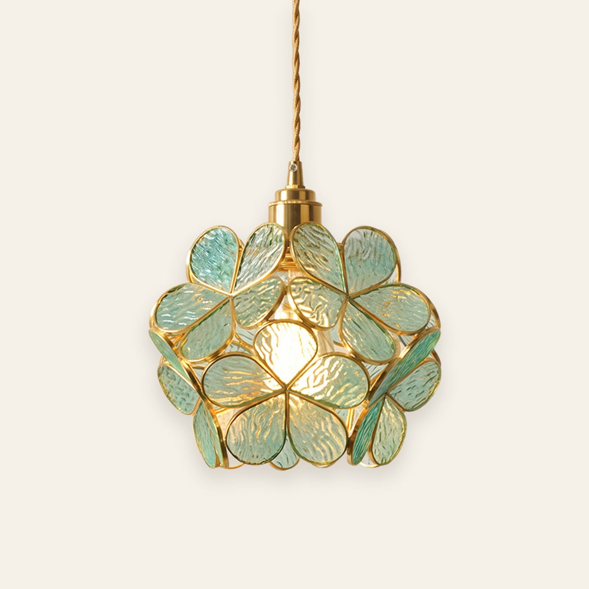 Halesworth pendant light with a round shade of sea green textured glass petals edged in brass, lit