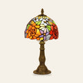 Hartest stained glass table lamp with a leaded shade of orange and red roses on a bronze finish base, cream background