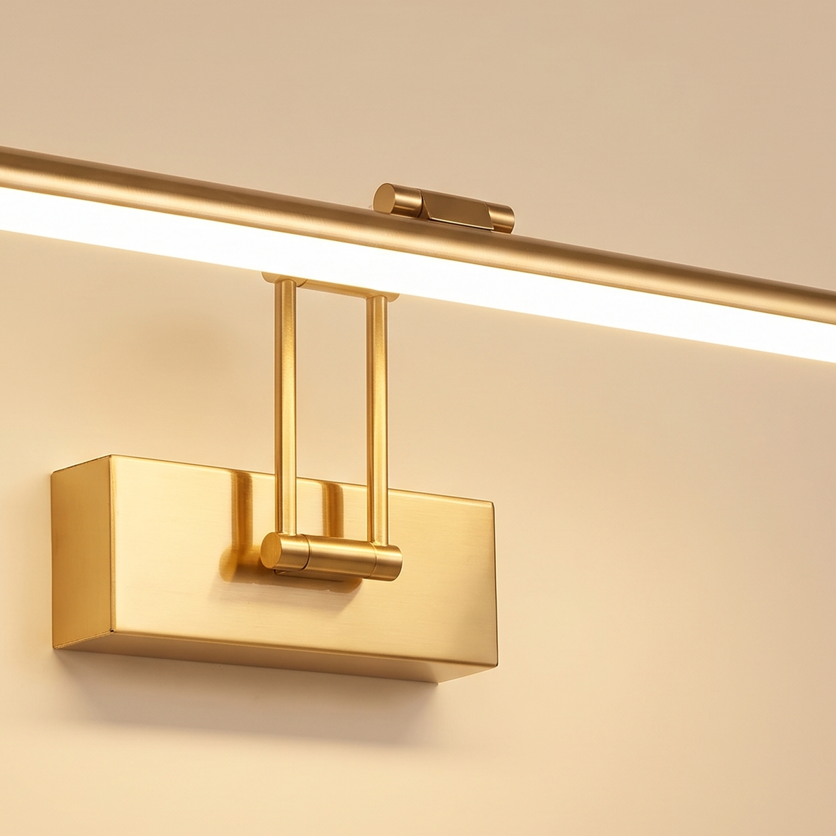 Close up of the brushed gold Helmingham picture light: the slim tube bar, its glowing diffuser, the arms and the wall box