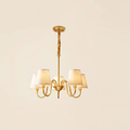 Henham 5 arm brass coloured chandelier with cream linen shades, lit, cream background