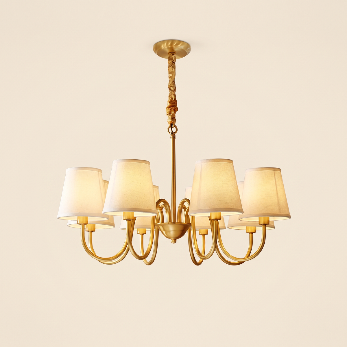 Henham 8 arm brass coloured chandelier with cream linen shades, lit, cream background