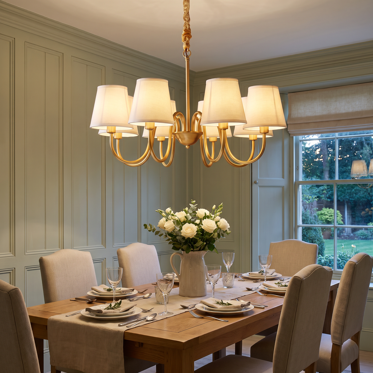 A lit Henham 8 arm chandelier with linen shades over an oak dining table in a panelled dining room