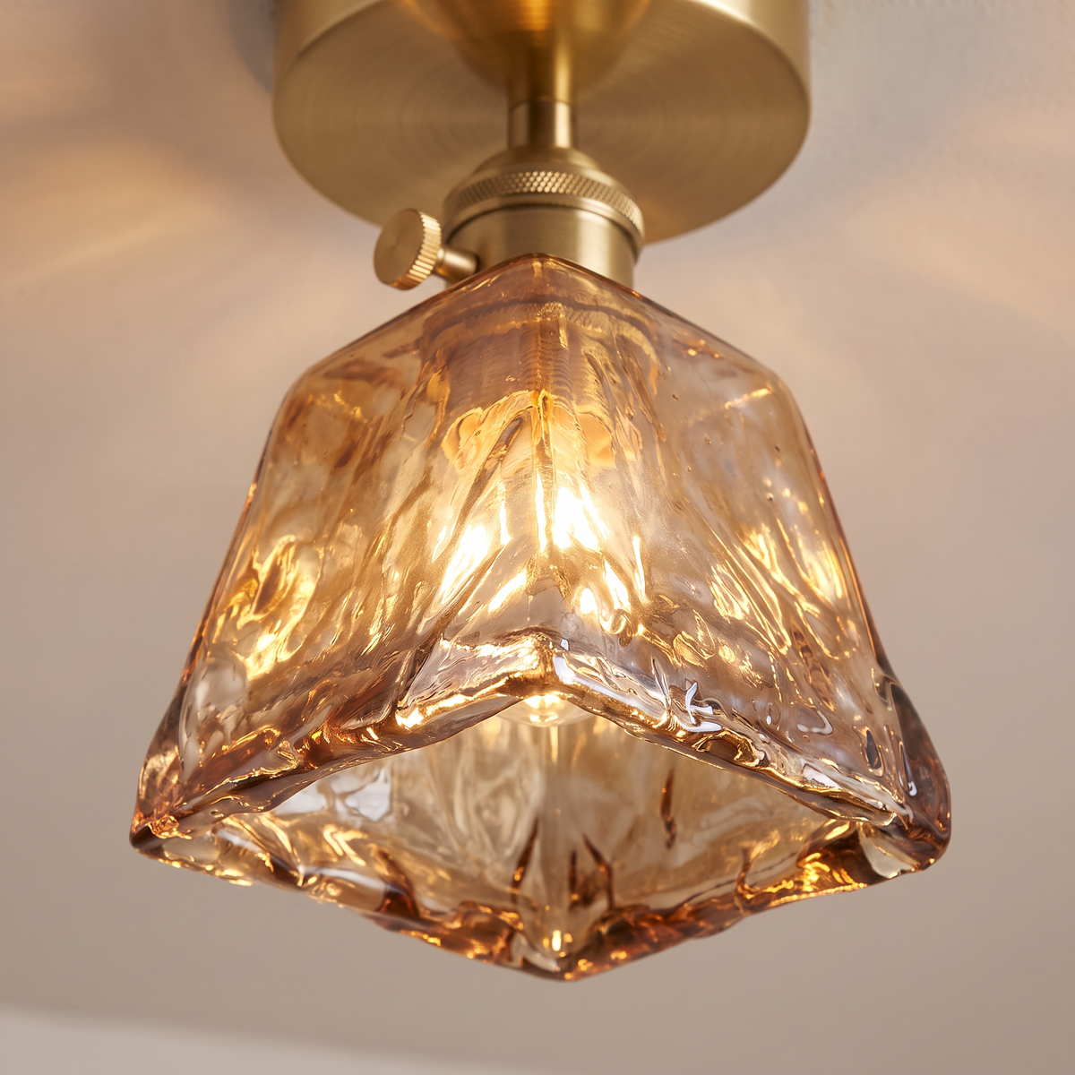 Close up of a lit Heveningham shade showing the rippled amber ice glass and the brass turn switch