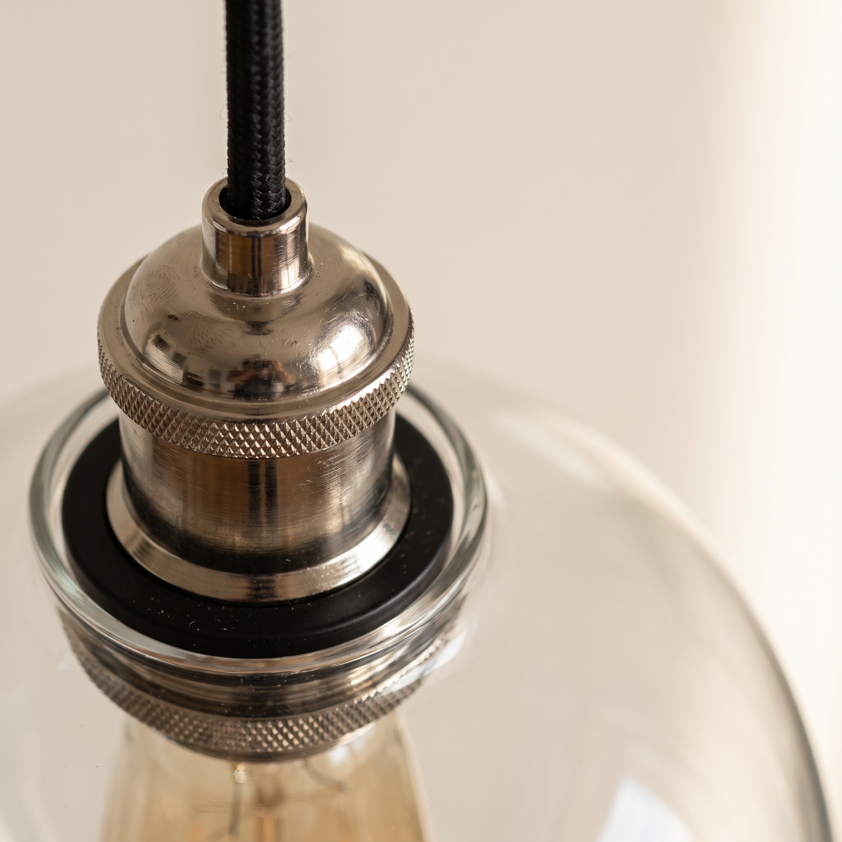 Close detail of the bright nickel collar and clear glass shade of the Lumira pendant