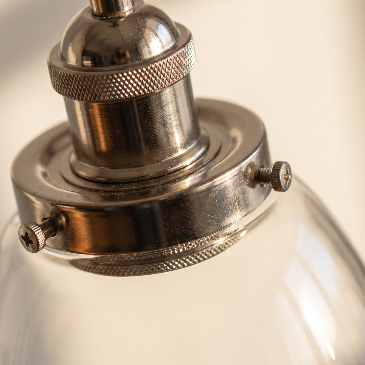 Close detail of the bright nickel collar and smooth glass shade of the Calvara pendant