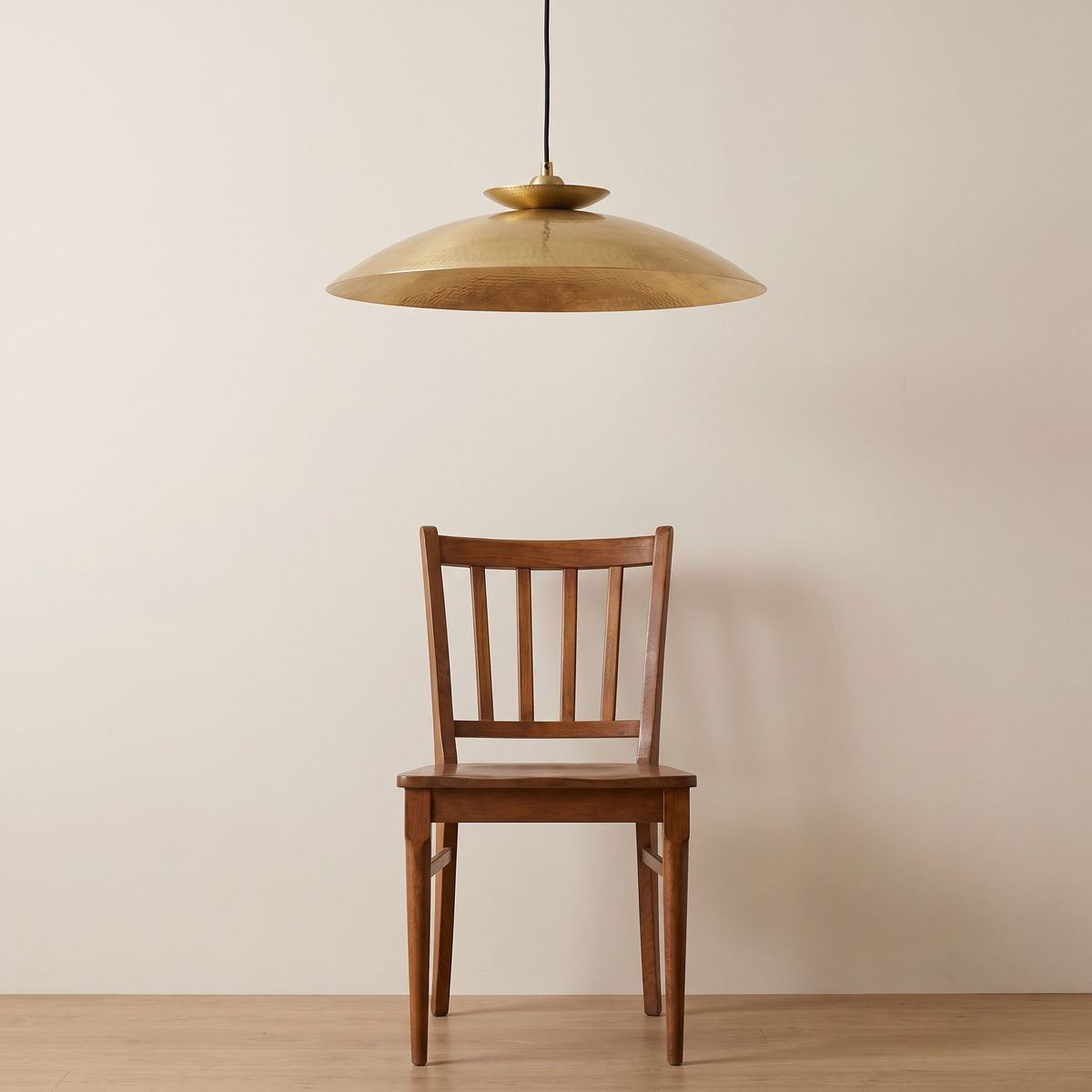 Halvern brass disc pendant shown above a dining chair for size reference