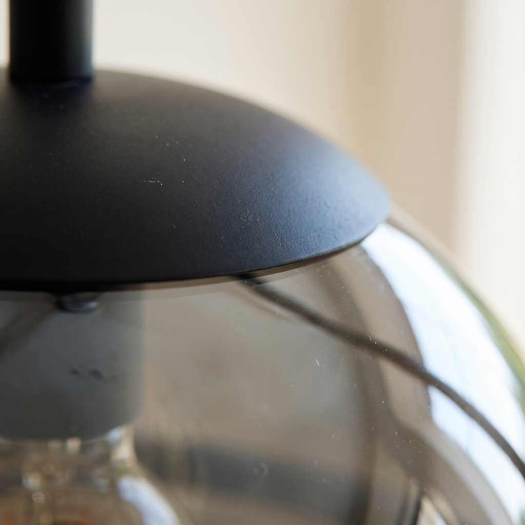 Close detail of the matt black collar and smoked glass shade of the Noctis pendant