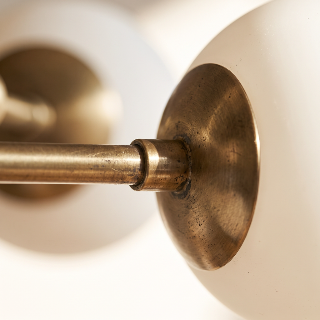 Close detail of a brass arm and opal glass globe on the Aurelle chandelier